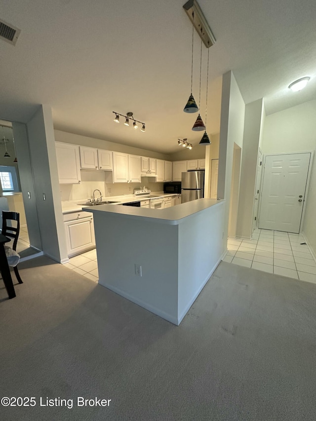 kitchen featuring vaulted ceiling, hanging light fixtures, stainless steel fridge, light colored carpet, and white cabinets