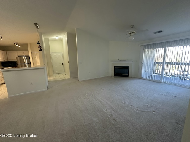 unfurnished living room with light colored carpet and ceiling fan