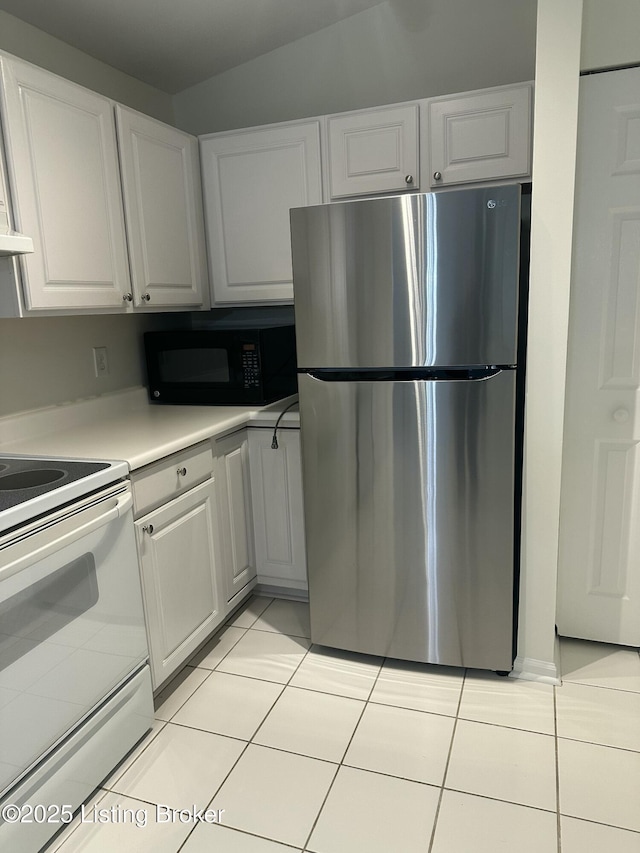 kitchen featuring stainless steel refrigerator, white cabinetry, white electric range, and light tile patterned floors