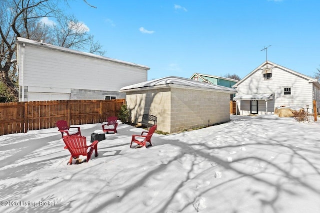 snow covered back of property with a storage unit