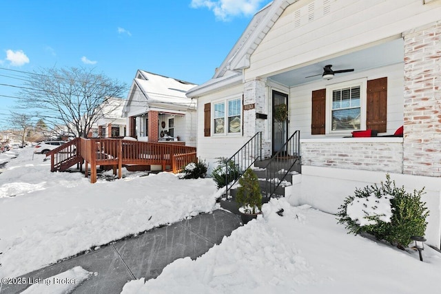 snow covered property entrance with ceiling fan