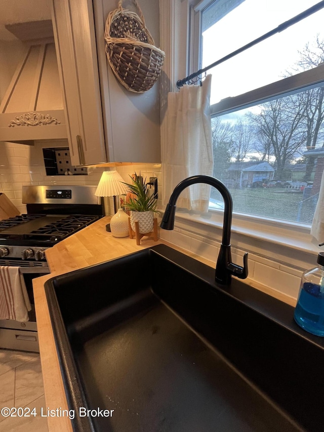 kitchen with decorative backsplash, stainless steel gas stove, plenty of natural light, and sink