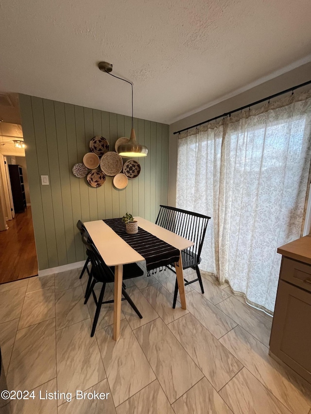 dining space with wood walls and a textured ceiling