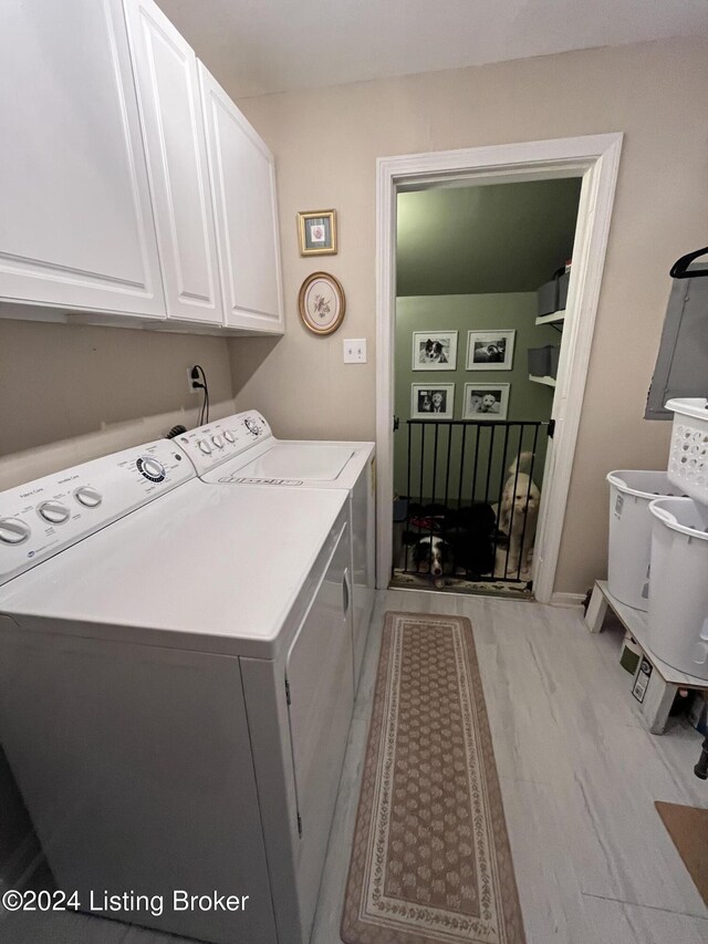 clothes washing area featuring cabinets, independent washer and dryer, and light hardwood / wood-style floors