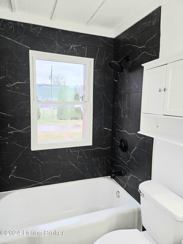 bathroom featuring tiled shower / bath and toilet