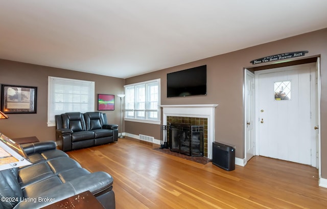 living room featuring wood-type flooring and a tiled fireplace