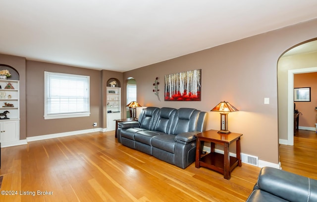 living room featuring built in shelves and hardwood / wood-style floors