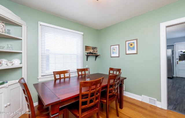 dining area with built in shelves and wood-type flooring