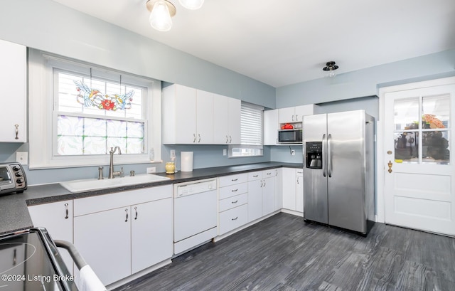 kitchen with stainless steel appliances, white cabinetry, dark wood-type flooring, and sink