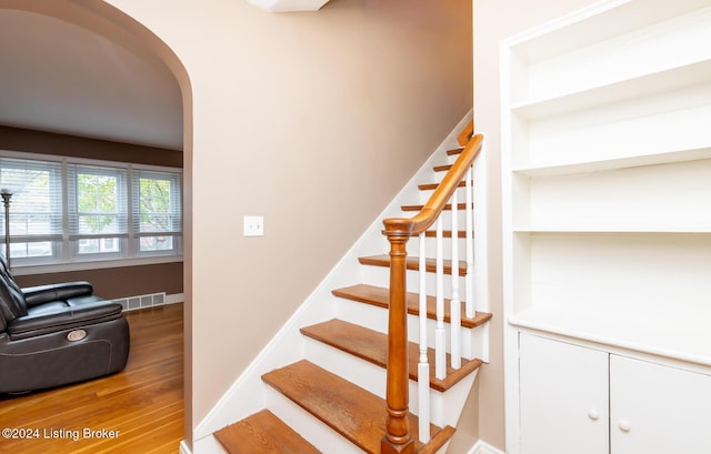 stairs with built in features and wood-type flooring