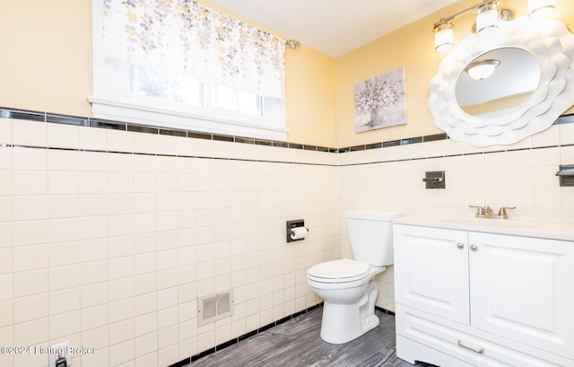 bathroom with vanity, wood-type flooring, tile walls, and toilet