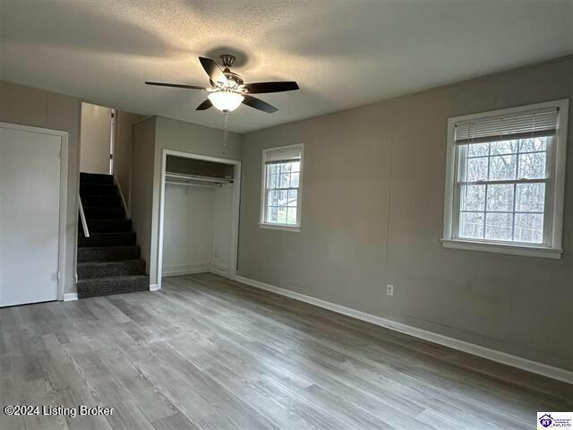 unfurnished bedroom featuring ceiling fan, a closet, hardwood / wood-style floors, and a textured ceiling