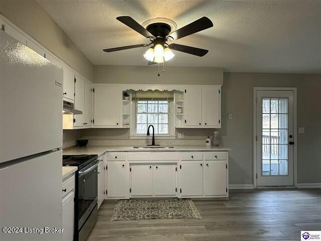 kitchen with black / electric stove, white cabinetry, sink, and white refrigerator