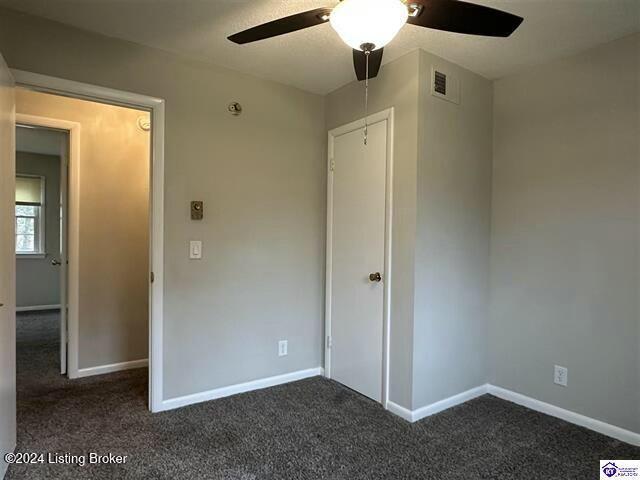 unfurnished bedroom with ceiling fan and dark carpet