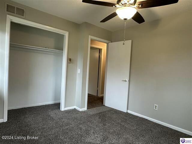 unfurnished bedroom featuring ceiling fan, a closet, and dark carpet