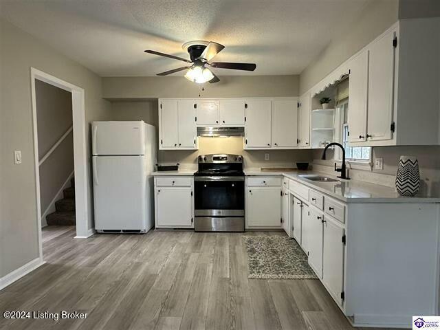 kitchen featuring white refrigerator, sink, light hardwood / wood-style flooring, electric range, and white cabinetry