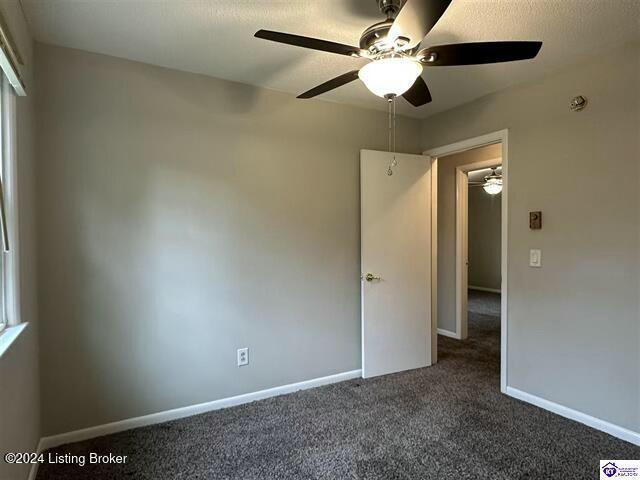 unfurnished room featuring dark colored carpet and ceiling fan