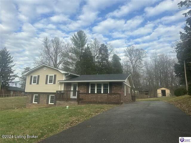 tri-level home featuring a front lawn and a storage unit