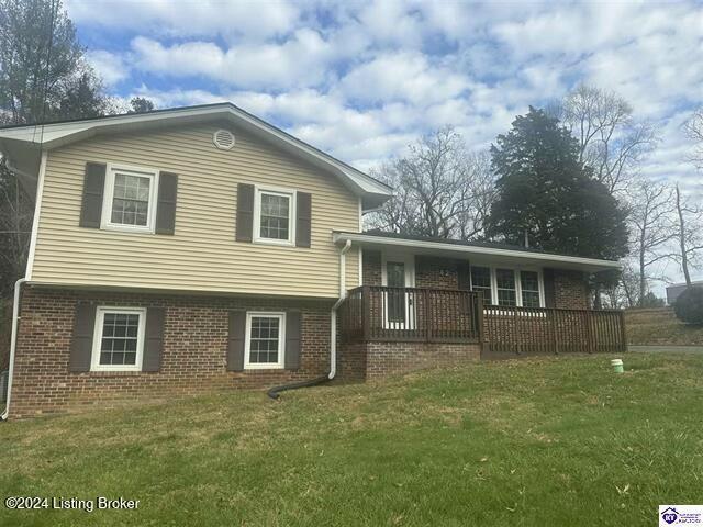 tri-level home with a wooden deck and a front lawn