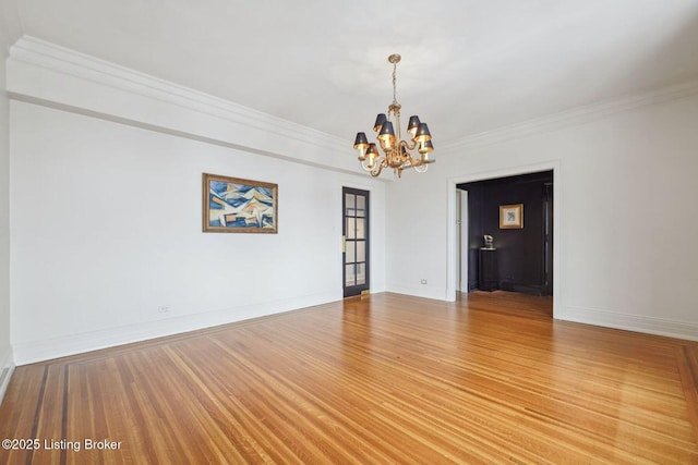 spare room with an inviting chandelier, ornamental molding, and hardwood / wood-style flooring