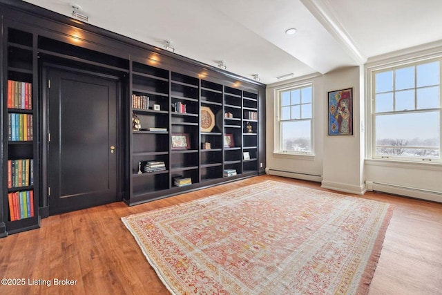 living area with a baseboard heating unit, crown molding, and hardwood / wood-style floors