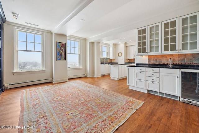 kitchen with light hardwood / wood-style floors, baseboard heating, white cabinetry, and wine cooler