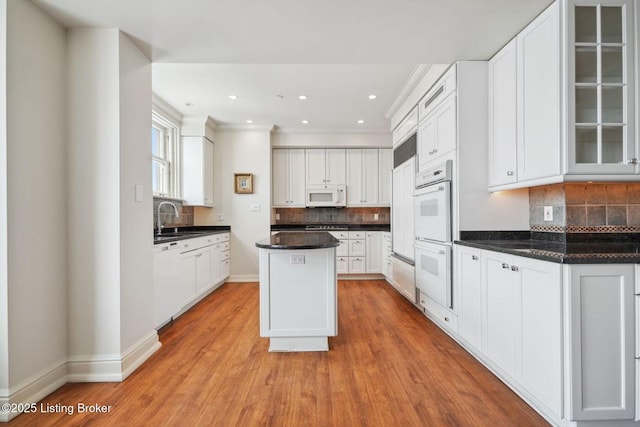 kitchen featuring white cabinetry, sink, a center island, and white appliances