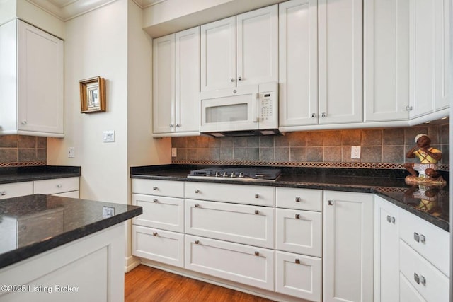 kitchen featuring backsplash, white cabinetry, stainless steel gas cooktop, and dark stone countertops