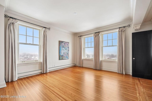 spare room featuring baseboard heating, light hardwood / wood-style flooring, and ornamental molding