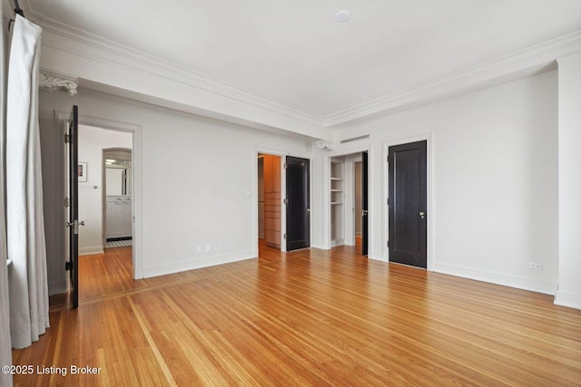 unfurnished room featuring built in shelves, crown molding, and light hardwood / wood-style floors