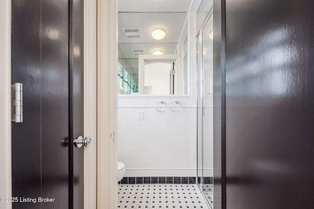 bathroom featuring toilet, tile walls, and walk in shower