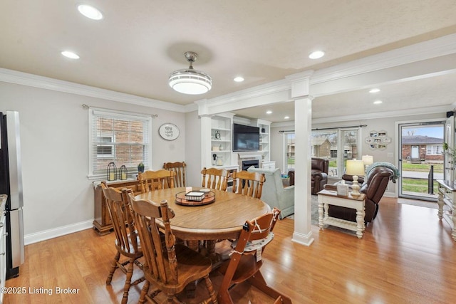 dining area with light wood-type flooring, crown molding, and decorative columns