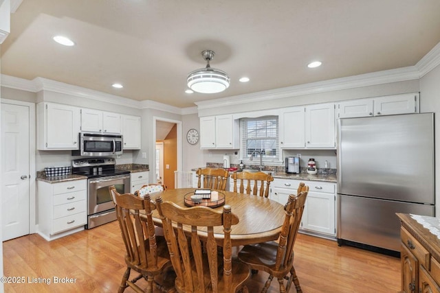 kitchen featuring light hardwood / wood-style floors, white cabinetry, crown molding, and appliances with stainless steel finishes