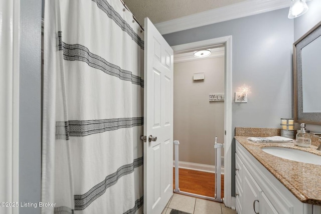 bathroom with tile patterned floors, crown molding, vanity, and a textured ceiling