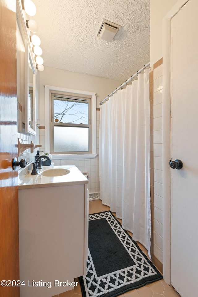 bathroom featuring vanity, tile patterned flooring, tile walls, a textured ceiling, and curtained shower