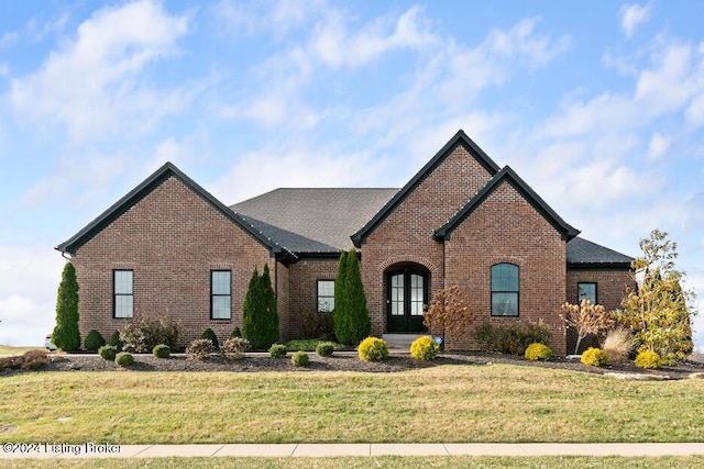 french provincial home featuring a front yard and french doors