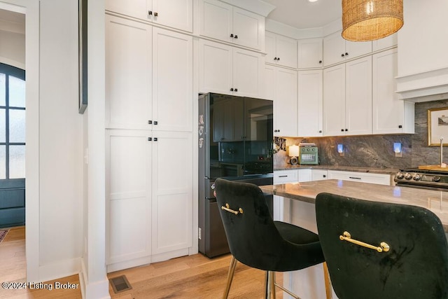 kitchen with backsplash, white cabinetry, black fridge with ice dispenser, and light hardwood / wood-style floors