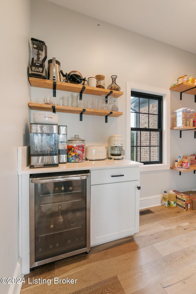 bar featuring white cabinets, light hardwood / wood-style floors, and beverage cooler