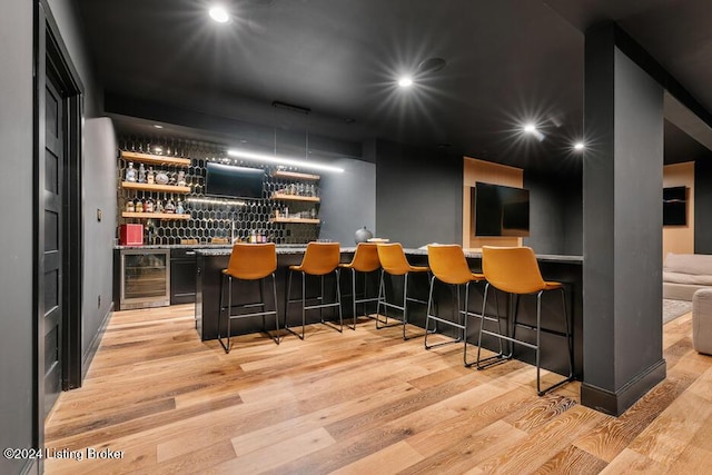 bar featuring beverage cooler and light hardwood / wood-style flooring