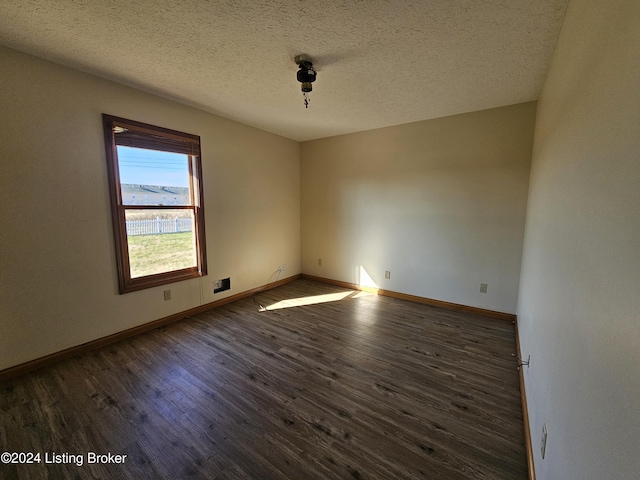 unfurnished room featuring dark wood-type flooring and a textured ceiling