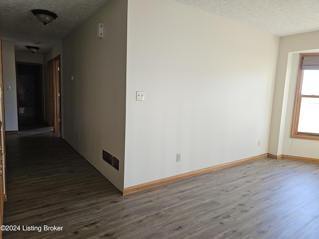 unfurnished room with a textured ceiling and dark hardwood / wood-style flooring