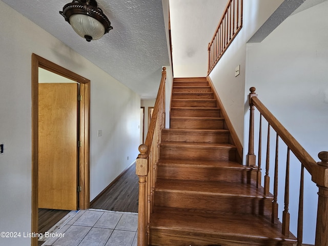 stairs with tile patterned floors and a textured ceiling