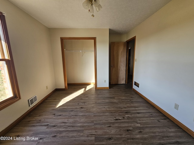 unfurnished bedroom with a textured ceiling, a closet, and dark hardwood / wood-style floors