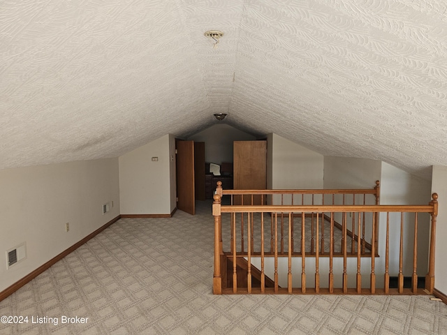 additional living space featuring a textured ceiling, carpet floors, and lofted ceiling