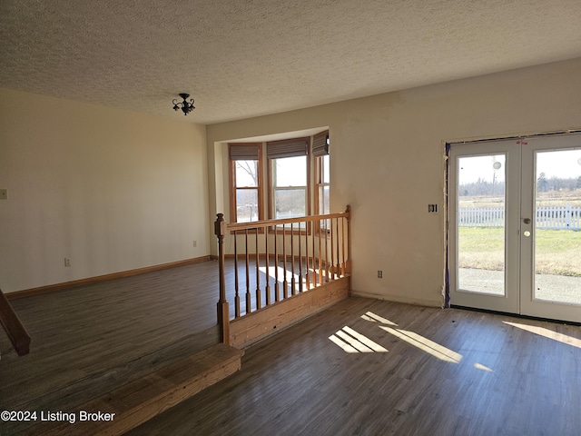 unfurnished room with french doors, dark wood-type flooring, and a textured ceiling