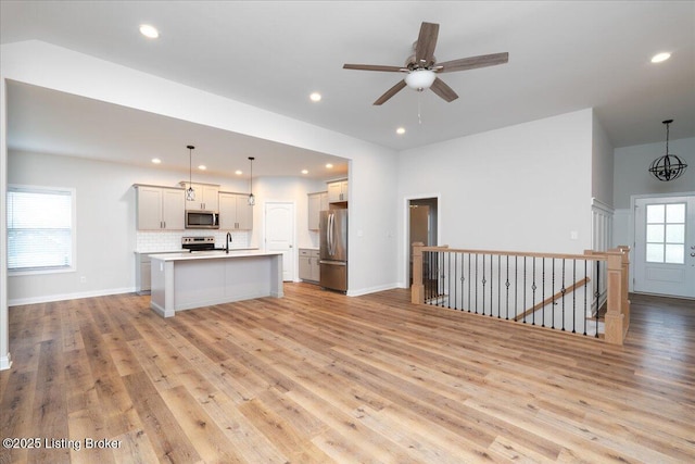 unfurnished living room with ceiling fan, sink, and light hardwood / wood-style flooring