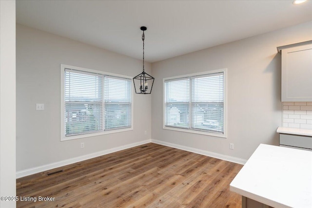 unfurnished dining area with hardwood / wood-style floors and an inviting chandelier