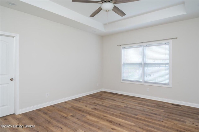 spare room featuring dark hardwood / wood-style flooring, a raised ceiling, and ceiling fan