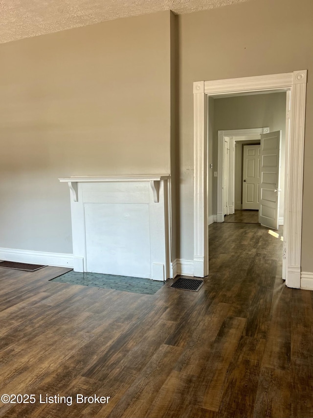 hall with a textured ceiling and dark wood-type flooring