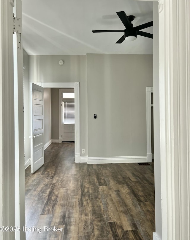 spare room featuring ceiling fan, baseboards, and dark wood-style flooring